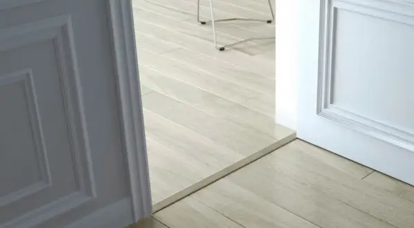 Une alternative barre de seuil discrète sépare deux pièces aux sols en parquet clair.