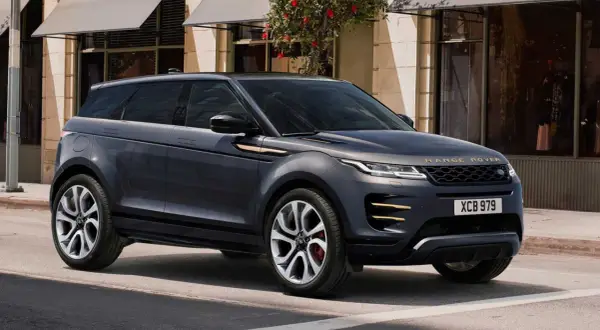 Dunkelgrauer Range Rover Evoque parkt vor einem Geschäft. Goldene Akzente zieren das Fahrzeug.