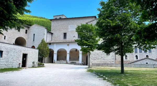 Cortile di un antico complesso monastico in pietra, con un portico ad archi. Ideale per chi cerca la fonte avellana come arrivare.