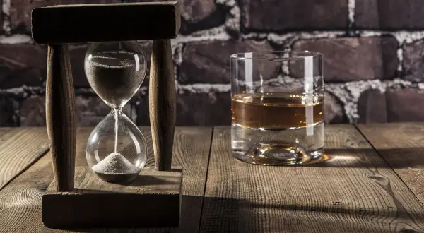 Kieliszek whisky i klepsydra symbolizują upływ czasu i szybkie spalanie alkoholu. Przyczyny tego zjawiska mogą być różne.