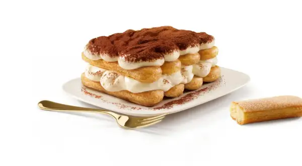 Un tiramisu généreux, fait avec 500g de mascarpone, est prêt à être dégusté. Une cuillère dorée et un biscuit à portée de main.