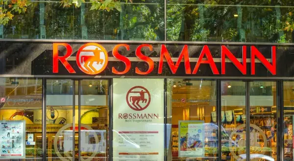 Logo Rossmann nad wejściem do drogerii. Warto wiedzieć, jak wywołać zdjęcia w Rossmannie, bo to popularna usługa.