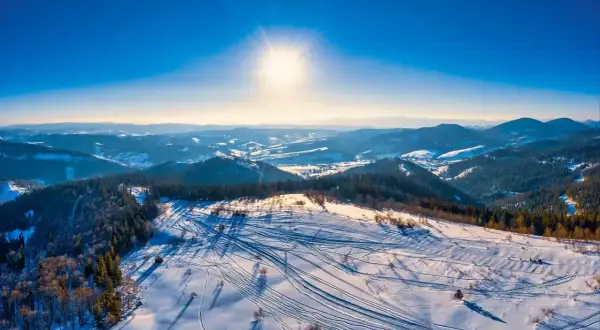 Sonniger Tag im Riesengebirge Skigebiet. Spuren im Schnee zeugen von einem lebhaften Tag auf den Pisten.
