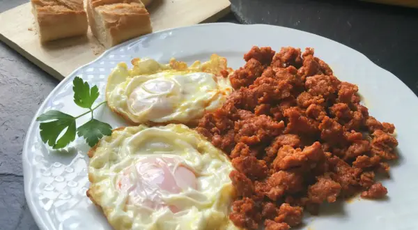 Dos huevos fritos y picadillo de chorizo, ideal para unas deliciosas recetas con picadillo de chorizo. Pan rústico al lado.