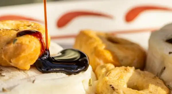 Une délicieuse entrée italienne : des taralli croustillants arrosés de glaçage balsamique sur un lit de fromage frais aux herbes.