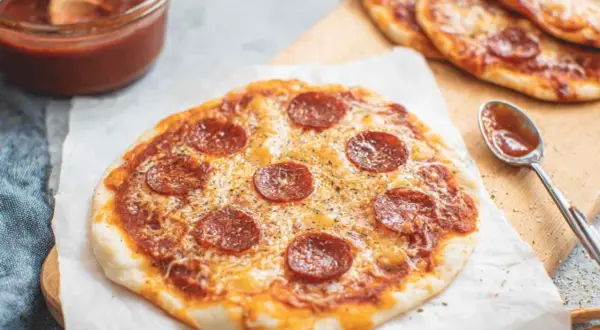 Pyszna pizza z tortilli z pepperoni i serem, obok miseczka sosu.
