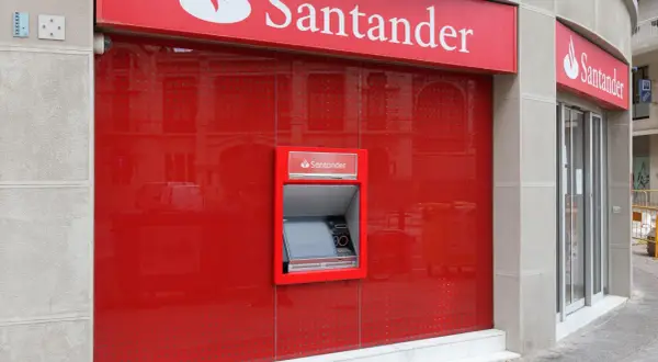 Bankomat Santander Platinum Konserwatywny na czerwonej, lśniącej ścianie.