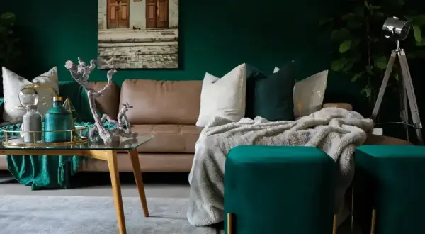 Elegancka, brązowa kanapa w salonie, otoczona zielenią i złotymi dodatkami. Inspiracje dla miłośników luksusowych wnętrz.