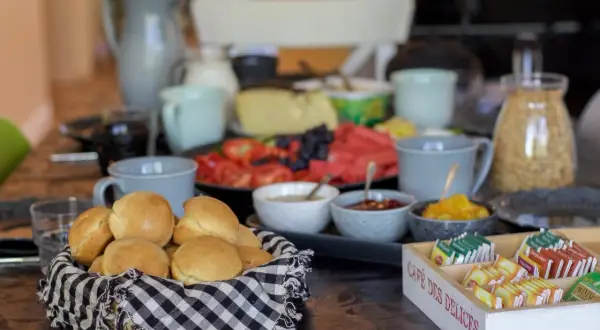 Frukostbuffé med korg full av nybakade scones över natten, frukt, ost och te.