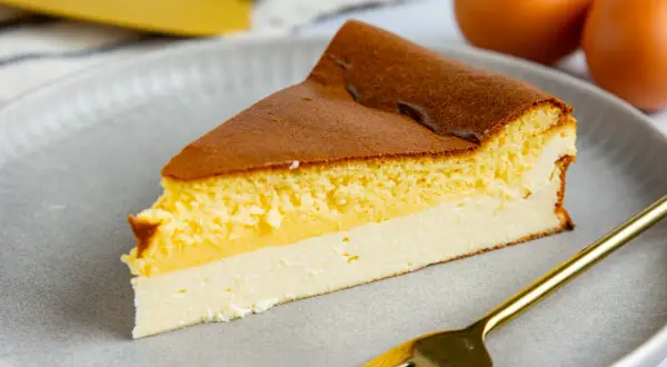 Ein saftiges Stück Eierschecke auf einem grauen Teller, bereit zum Genuss. Dieses Eierschecke Rezept ist ein Klassiker.