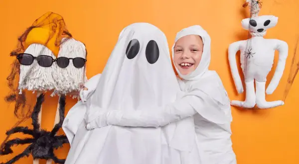 Dzieci w strojach duchów i mumii, idealne pomysły jak się przebrać na Halloween. Zabawne dekoracje i pajęczyny.