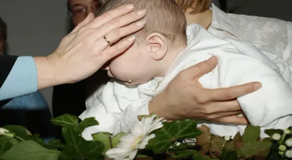 Rytuał chrztu: ręka matki błogosławi dziecko. Co zrobić że świeca po chrzcie? Zachowaj ją jako pamiątkę.
