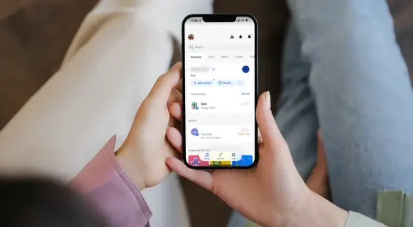 Osoba sprawdza transakcje na telefonie, widoczny jest debet na koncie Revolut po zakupach w Spar.