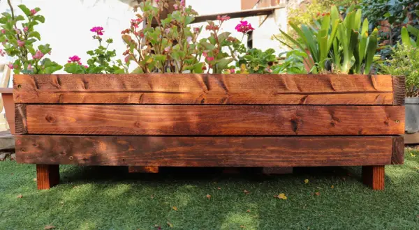 Mesa de cultivo de madera con flores y plantas verdes. Ideal para aprender cómo hacer una mesa de cultivo.