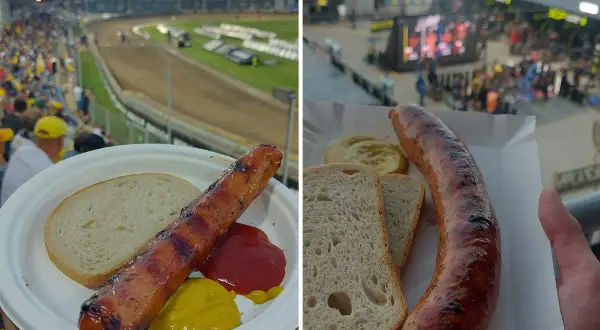 Kiełbasa z grilla i chleb na talerzu, w tle stadionowa atmosfera i trybuny pełne kibiców.