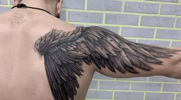 Realistyczny tatuaż skrzydła na ramieniu. Symbolika wolności i siły.