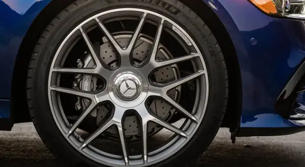 Primo piano della ruota di un'auto blu con cerchi AMG e dischi freno forati, per un controllo freni auto impeccabile.