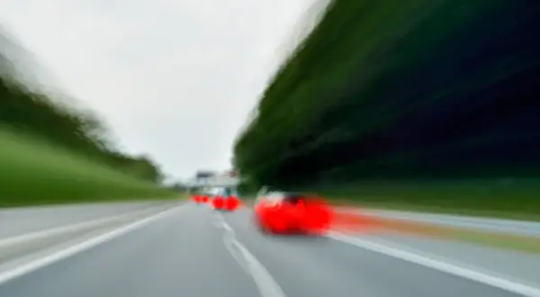 Dynamiczne wyprzedzanie z lewej strony na autostradzie. Czerwone światła samochodów zamazane przez ruch.