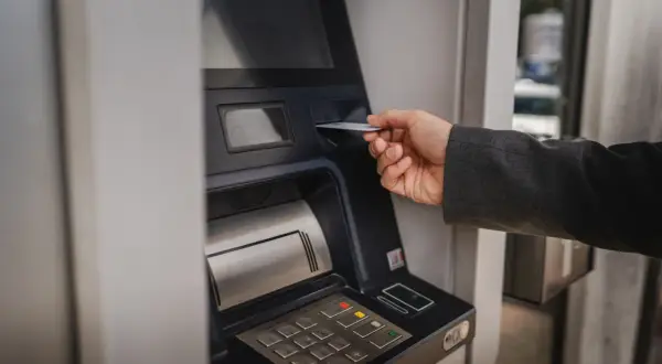 Dłoń wsuwa kartę do bankomatu PKO. Zastanawiasz się, ile można wyplacic w bankomacie PKO? Sprawdź to!