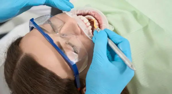 Dentysta wykonuje zabieg higienizacji zębów. Czas ten jest krótki, a efekt olśniewający.