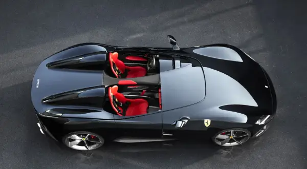 Czarny Ferrari Monza SP1 z czerwonymi siedzeniami, gotowy do jazdy po torze.
