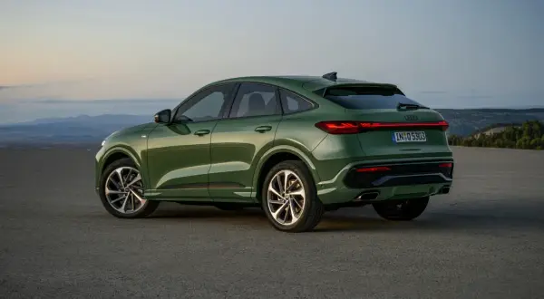 Zielony q5 audi z elegancką linią dachu, zaparkowany na pustkowiu o zachodzie słońca.