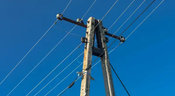 Betonowy słup energetyczny z przewodami na tle błękitnego nieba.