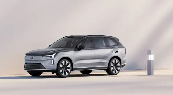 En silverfärgad elbil laddas vid en laddstation. Undrar du vad kostar en ny bil? Denna Volvo ser futuristisk ut.