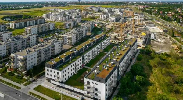 Nowe osiedle z zielonymi dachami, w tle budowa i miasto. Brak śladów powodzi.
