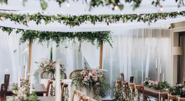 Udekorowane zielenią i kwiatami stoły tworzą magiczny styl boho na wesele. Delikatne tkaniny i girlandy dodają romantyzmu.