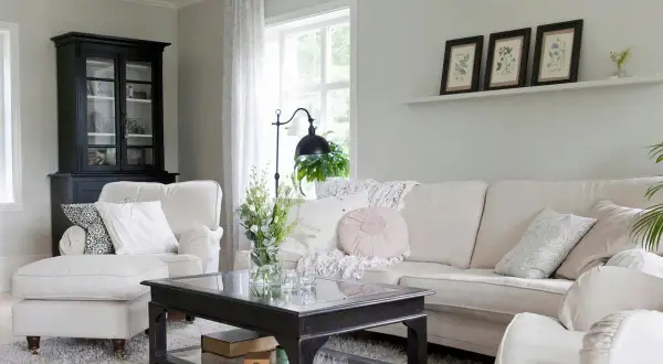 Gemütliches Wohnzimmer mit einem Sofa und Sessel in off white farbe, einem schwarzen Schrank und einem Couchtisch.