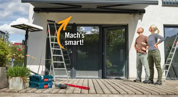 Sonnenschutz Terrasse Ideen: Mann und Frau blicken nach oben, während Werkzeug und Leiter auf der Holzterrasse bereitstehen.