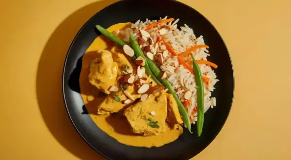 Aromatyczne curry z kurczakiem w kremowym sosie, podane z ryżem, fasolką szparagową i migdałami.