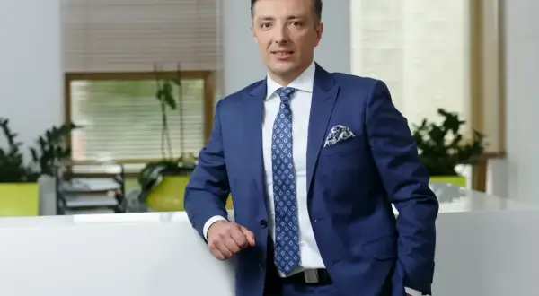 Mężczyzna w granatowym garniturze stoi w nowoczesnym biurze.