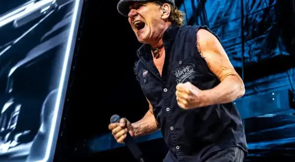 Brian Johnson z ACDC Polska śpiewa z pasją na koncercie, w czapce i kamizelce Harley-Davidson.