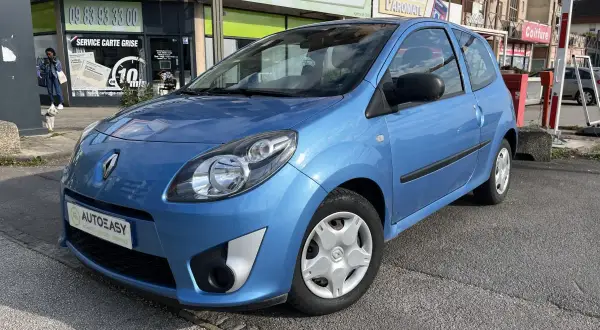 Une Twingo 2 phase 2 bleue, garée devant un commerce.