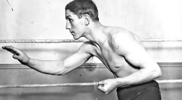 Georges Carpentier, a legendary boxer, poses in the ring, his muscular physique ready for action.