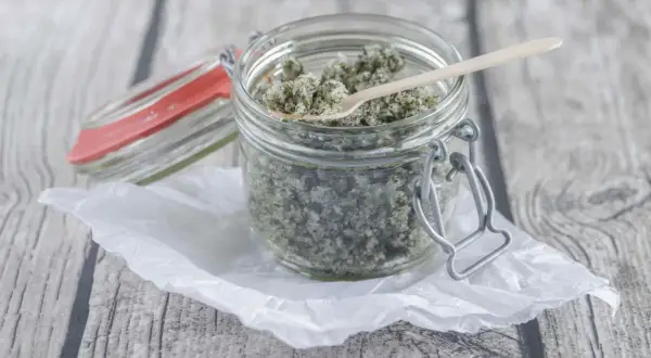 Ein Glas mit selbstgemachtem Kokos Peeling, bereit zur Anwendung. Ein kleiner Holzlöffel liegt darin.