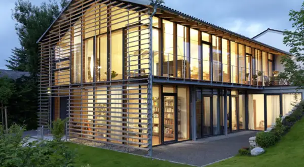 Modernes Haus mit Satteldach, das durch eine Glasfassade und horizontale Lamellen eine neue Interpretation erfährt.