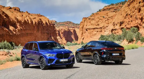 Dwa BMW X5M i X6M w malowniczym kanionie. Jeden niebieski, drugi czarny, gotowe na przygodę.