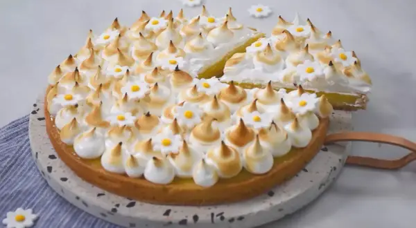 Une délicieuse tarte citron meringuée, ornée de petites fleurs en sucre, prête à être dégustée.