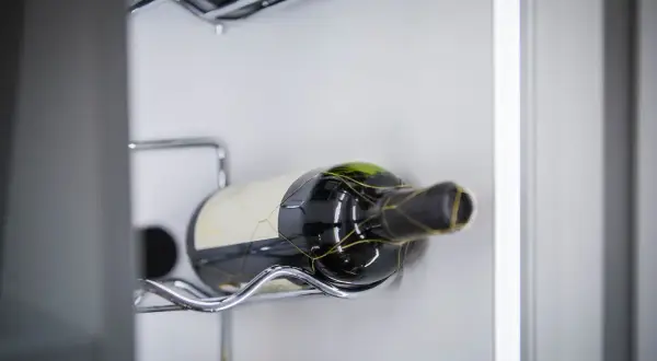 Eine Flasche Rotwein, die für die Lagerung von offenem Rotwein vorbereitet ist, liegt auf einem metallenen Gestell.