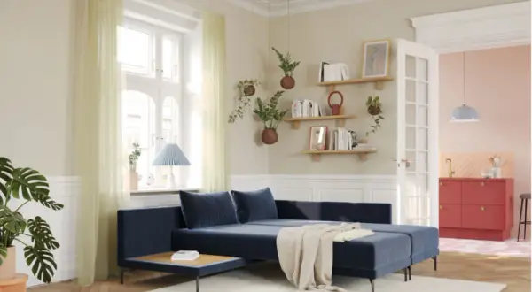 Gemütliches Wohnzimmer mit dunkelblauem Sofa, hellen Vorhängen und Regalen voller Bücher. Moderne Farben schaffen eine einladende Atmosphäre.