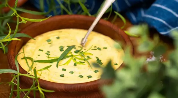 Krämig bearnaisesås i träskål, perfekt för ett enkelt bearnaisesås recept med stavmixer. Garnerad med färsk dragon.