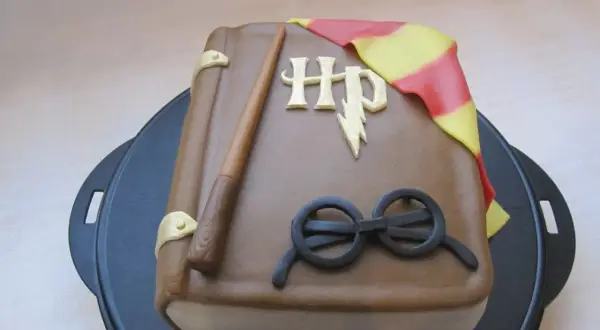 En tårta formad som en bok med Harry Potters trollstav, glasögon och Gryffindors halsduk. Ett magiskt harry potter tårta recept!