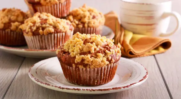 Pyszne muffinki drożdżowe z kruszonką na talerzykach, obok filiżanka kawy.
