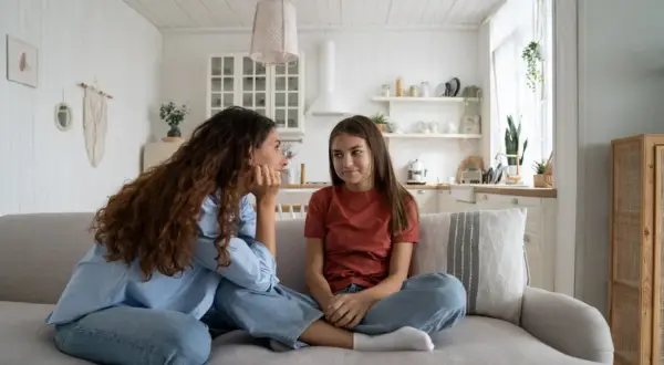 Mama rozmawia z nastolatką o zasadach w domu. Dziewczyna siedzi na kanapie, słuchając uważnie.