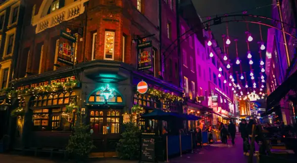 En livlig kväll i Soho, London, med The Blue Posts pub upplyst av julbelysning och neonskyltar.