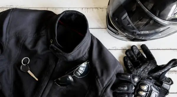 Czarna kurtka motocyklowa, kask, rękawice, okulary i kluczyk na białym tle.