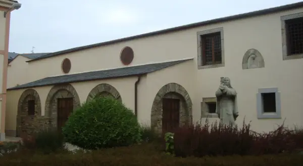 Fachada del convento de Santa Clara en Ribadeo, con arcos de piedra, ventanas y una estatua de monja.